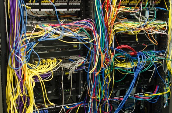 Data center view of tons of different colored wires connected to servers.