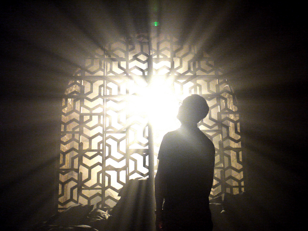 Man in shadow sees bright light through the window.
