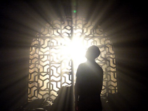 Man in shadow sees bright light through the window.