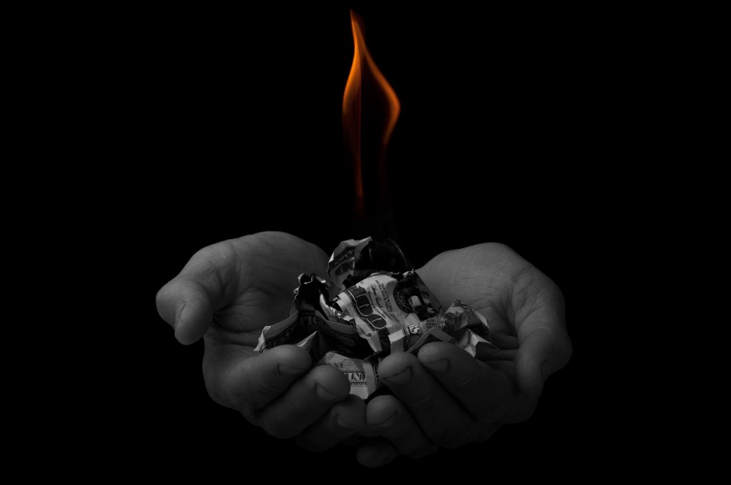 flame over dollars in hands