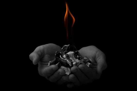 flame over dollars in hands