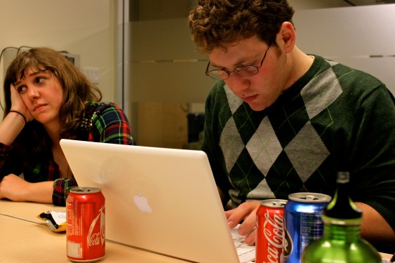 Workers in front of Mac laptop with Coke cans scattered around it.