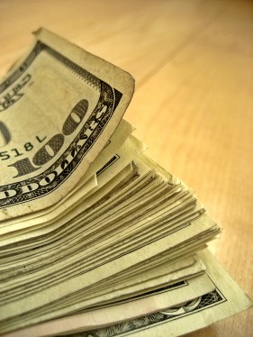 Pile of money with a hundred dollar bill on top.