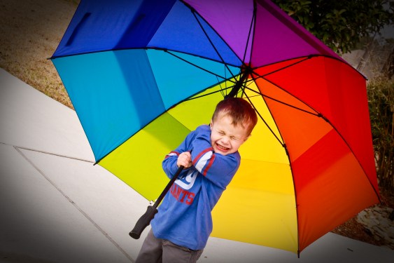 LIttle boy under huge umbrella.