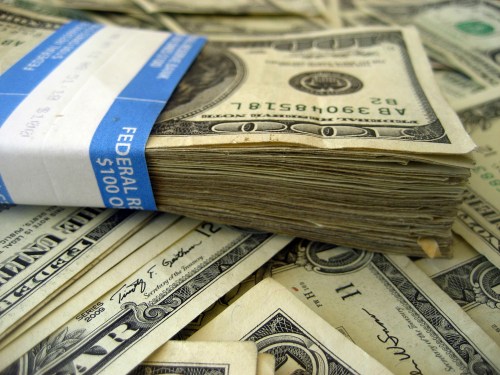Pile of US bills; packet of hundreds on top of loose one dollar bills.
