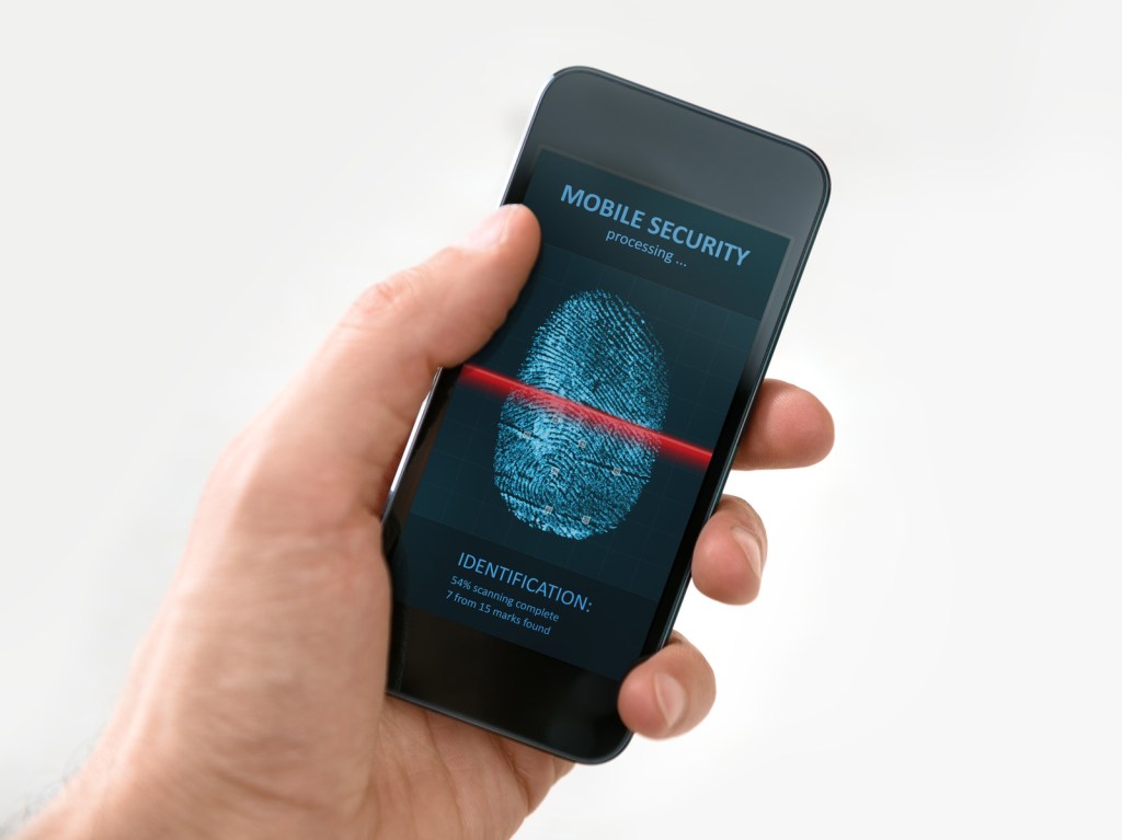 Hand holding a mobile phone while finger print gets scanned.