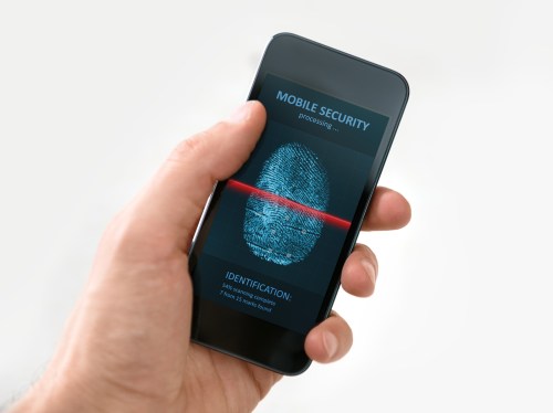 Hand holding a mobile phone while finger print gets scanned.