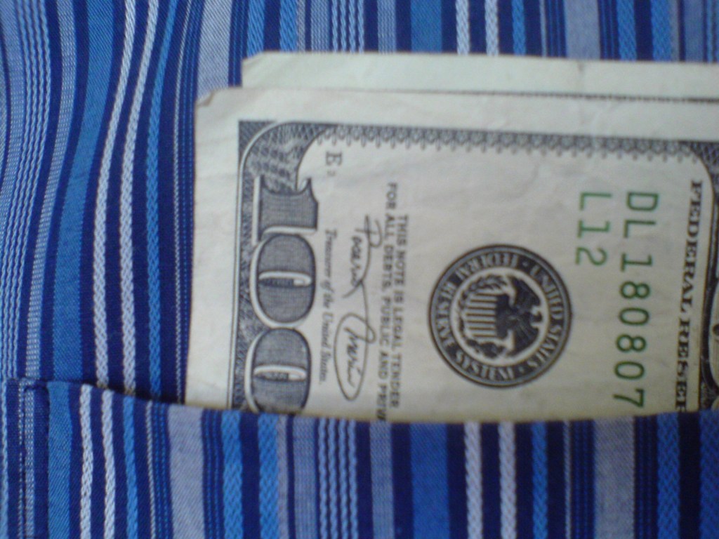One hundred dollar bills sticking out of a shirt pocket.