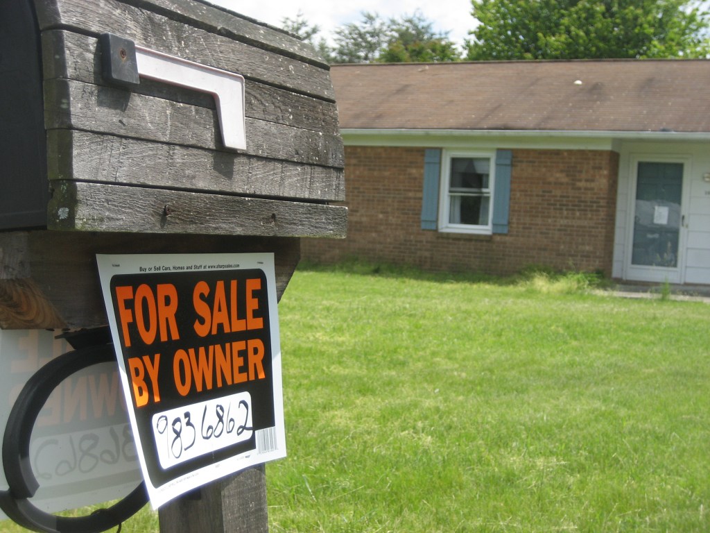 For Sale by Owner sign on mailbox in front of ranch house.