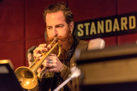 Trumpet player in front of Standard sign.