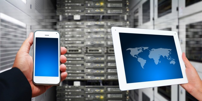 Hands holding mobile phone and tablet, superimposed over data center.