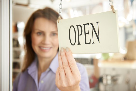Small business owner flipping Open sign on door.