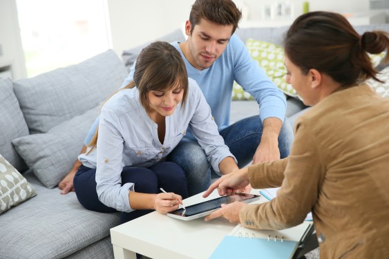 Couple signing an order on a tablet as saleswoman looks on.