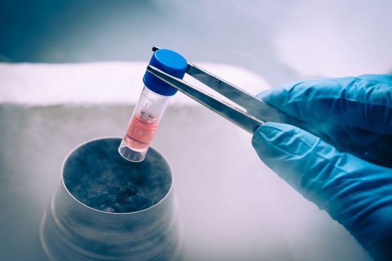 lab tech holding small vial using tweezers
