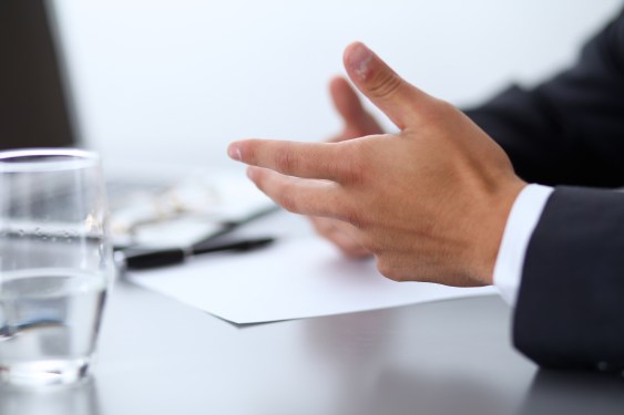 Close up hands discussing contract sitting on table.