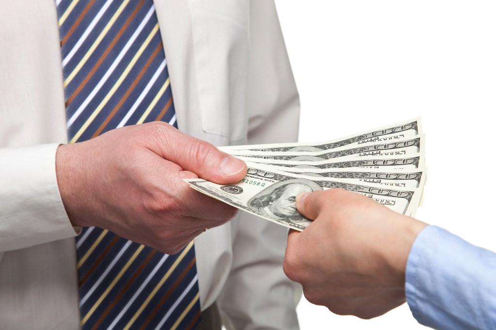 Person handing another person a stack of bills.