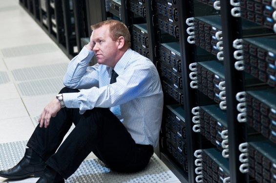 Frustrated IT executive sitting on floor of data center.