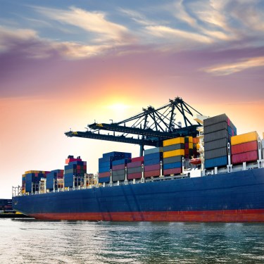 Cargo ship in port at sunset.