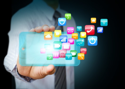 Business man holding a smart phone with apps flying out of it.