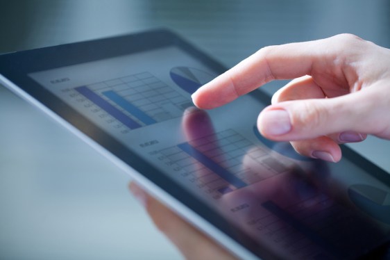 Close up of hand on tablet with business intelligence data displayed.