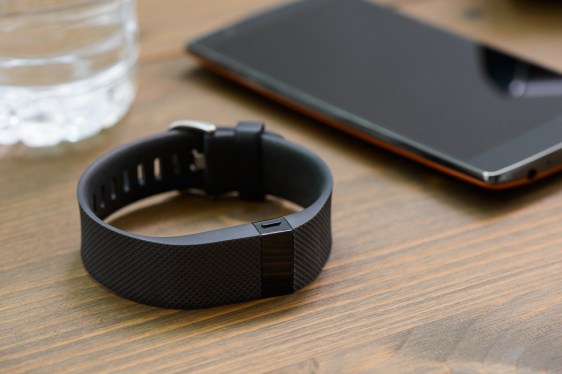 Table with glass of water, fitness wearable and smartphone on it.