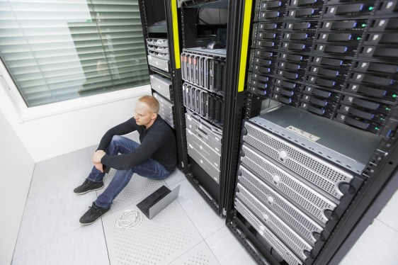 Distraught IT pro sitting on floor of data center.