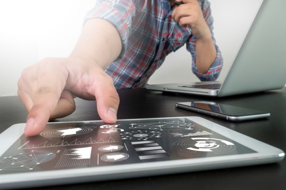 Man reaching for tablet with lots of data on it.