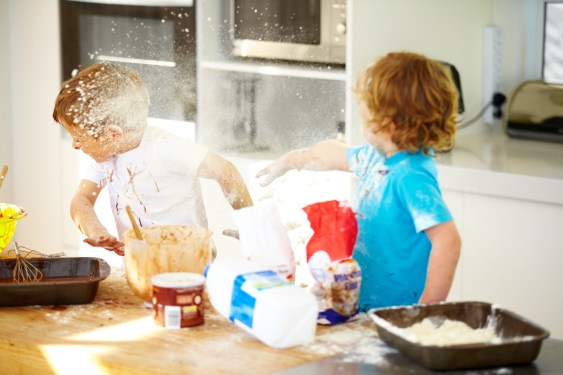 Boys in kitchen throwing flour at each other.