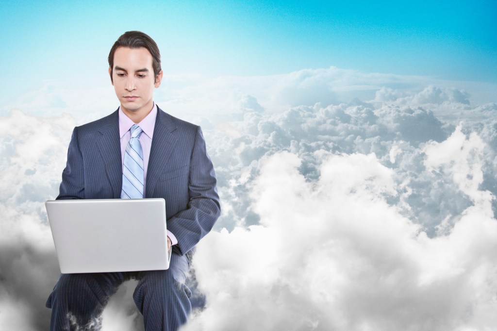 Business man sitting on cloud with laptop in hand.