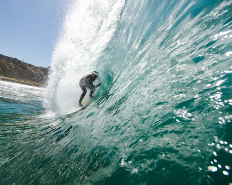 Surfer catching a wave inside the curl. Lip of wave hitting his head.