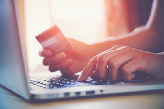 Person holding credit card at laptop.