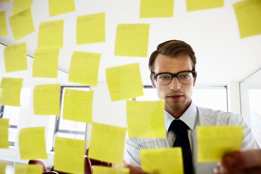 employee fixing sticky notes on a glass screen