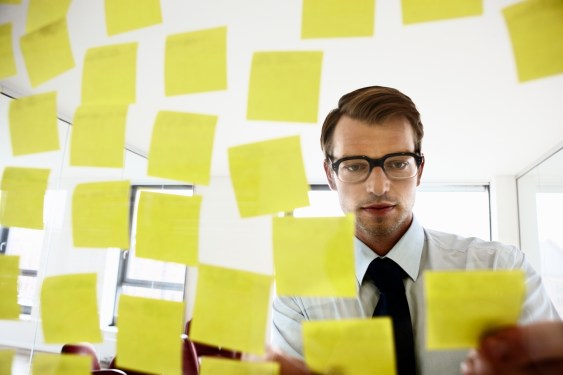 employee fixing sticky notes on a glass screen