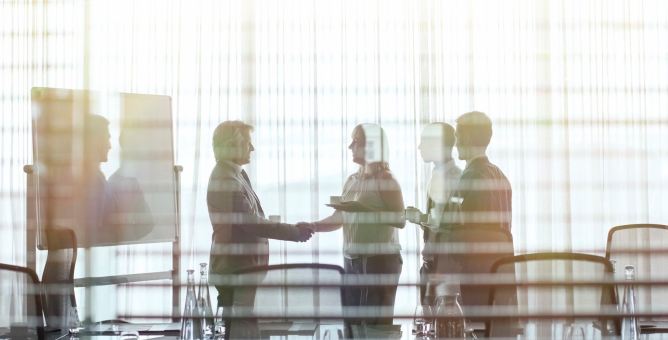 Business people standing in conference room shaking hands