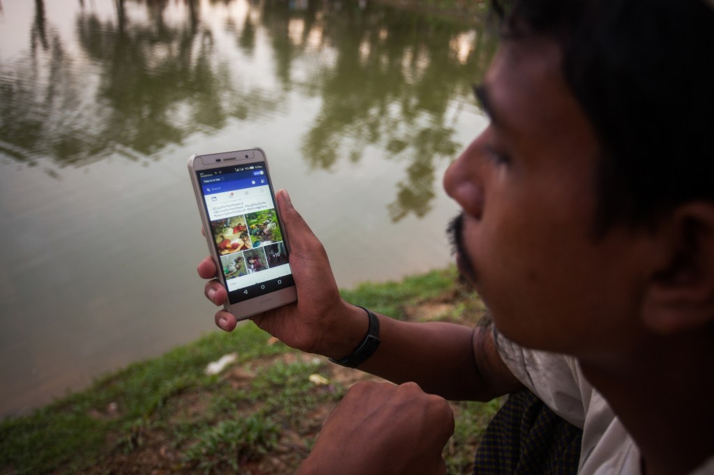man looking Facebook at his cell phone