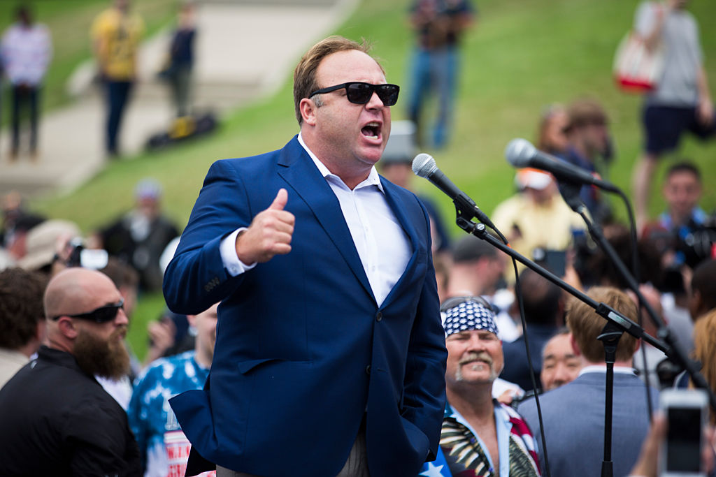 man standing at mic; Alex Jones