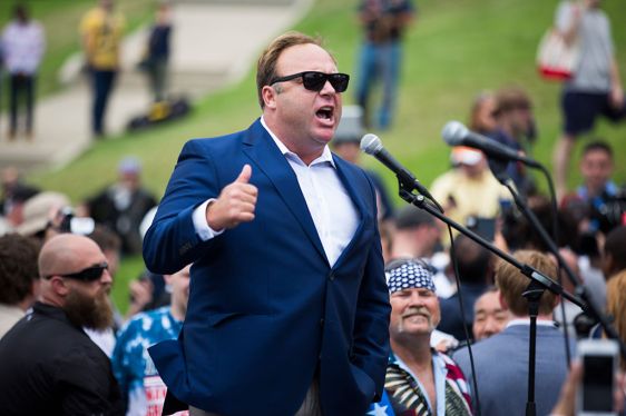 man standing at mic; Alex Jones