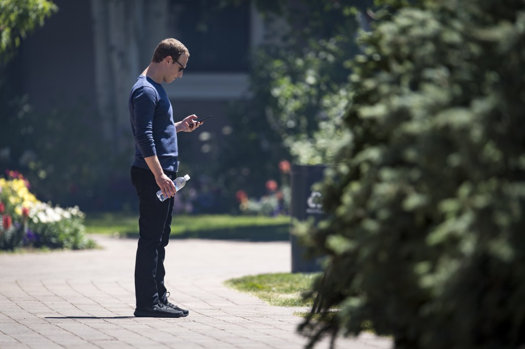 Mark Zuckerberg looks at his phone