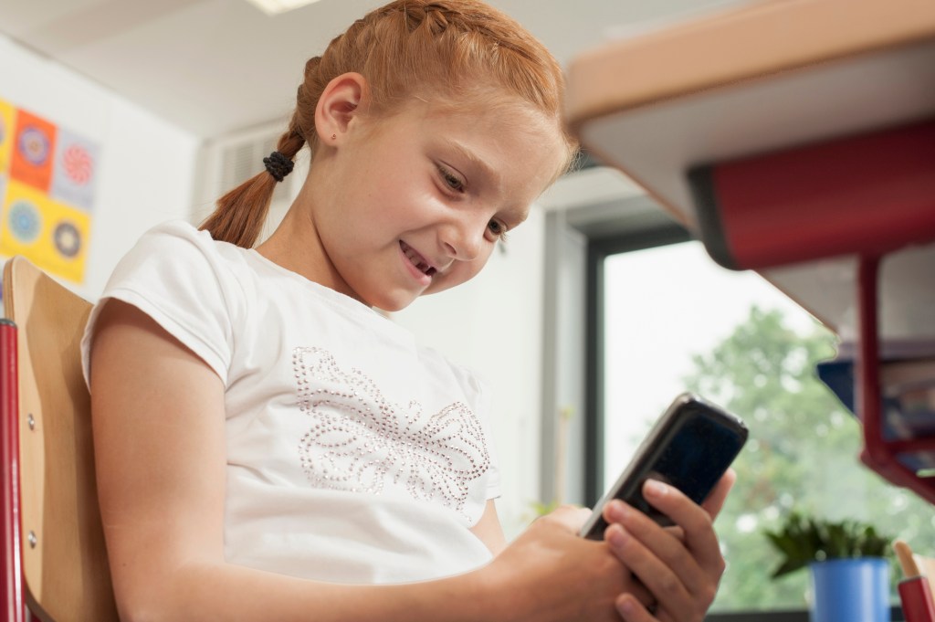 Low angle view of a schoolgirl using a smart phone in classroom