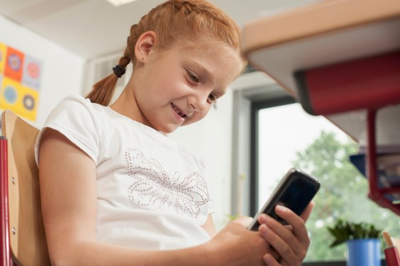 Low angle view of a schoolgirl using a smart phone in classroom