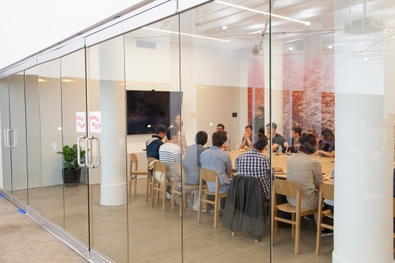 glass-walled conference room with people sitting at large table