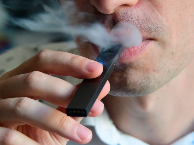 An illustration shows a man exhaling smoke from an electronic cigarette in Washington, DC on October 2, 2018.