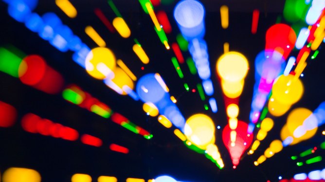 Close-up unfocused of lights of colors in the shape of circles and lines of colors blue, yellow and red on a black background. Spain.