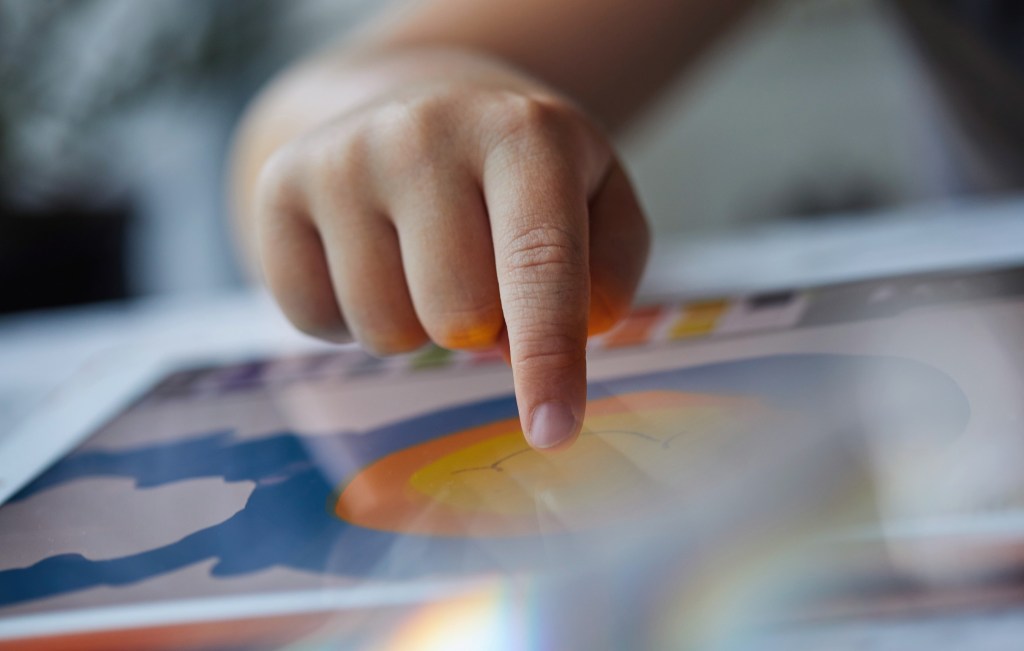 child's hand touching tablet