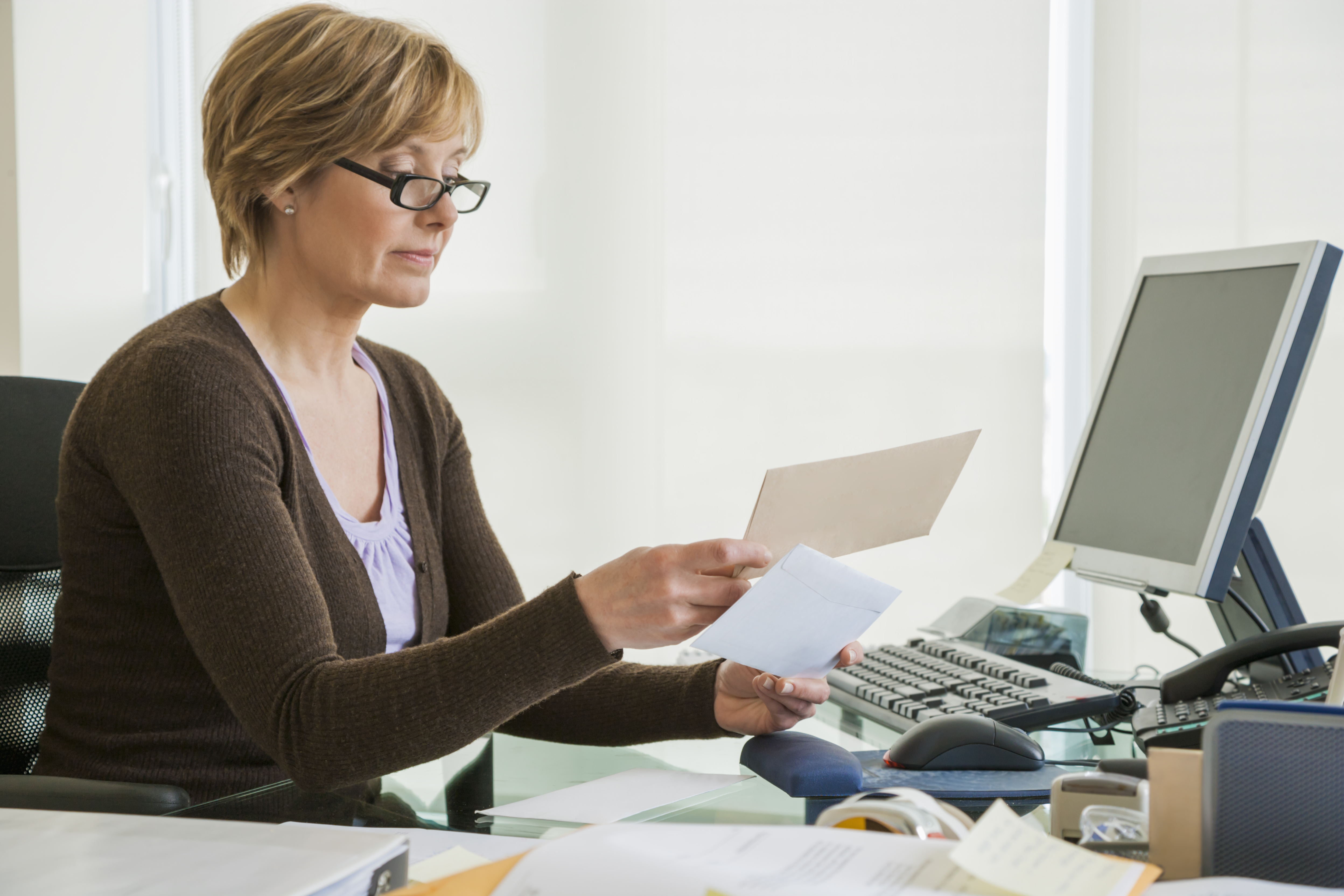Middle-aged woman looking at bills at computer GettyImages 518906520