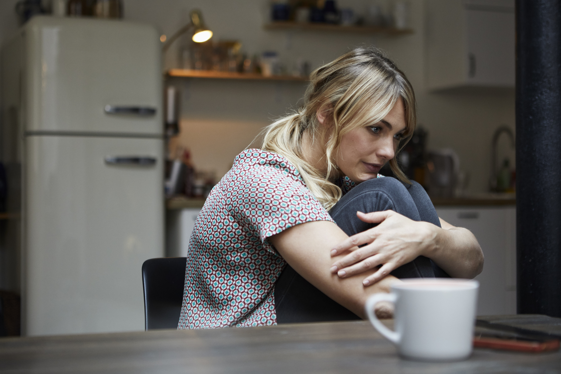 Portrait of pensive woman sitting at table in the kitchen GettyImages 919440232