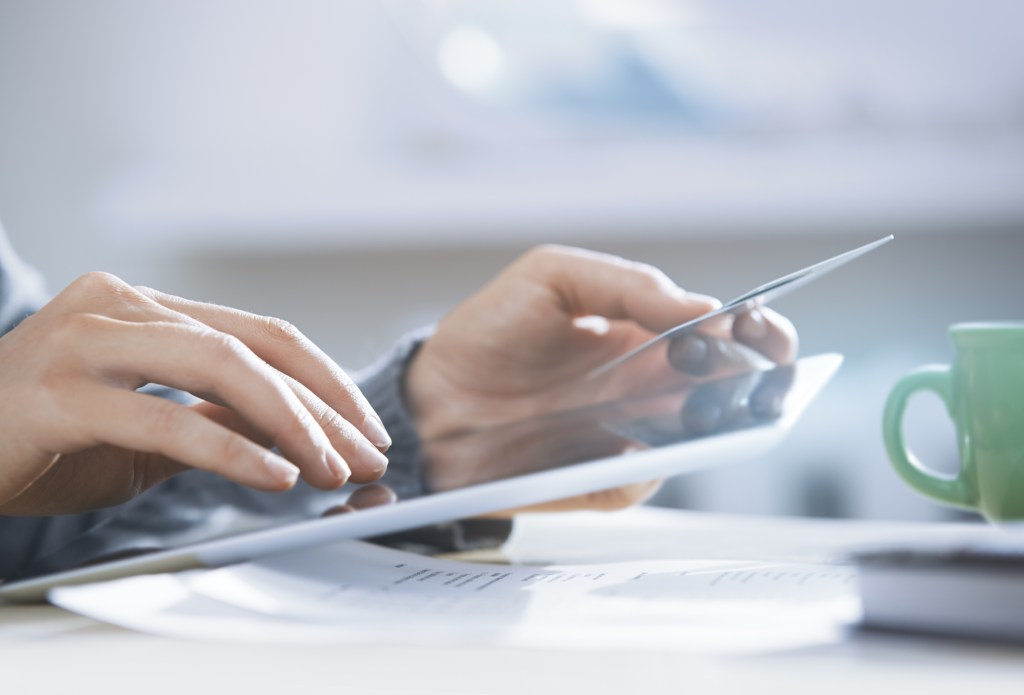 Hands of woman using digital tablet and credit card at home