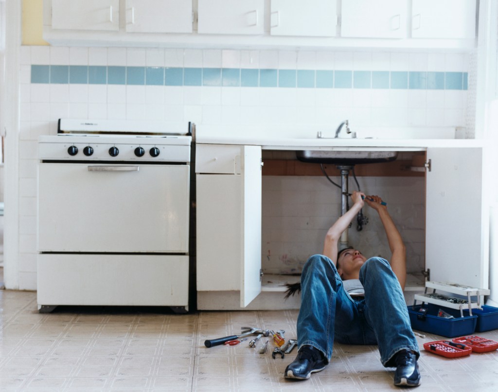 Woman with Toolbox Fixing Sink