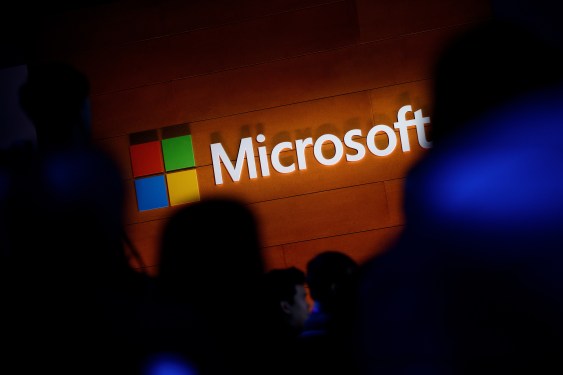 The Microsoft logo is illuminated on a wall during a Microsoft launch event