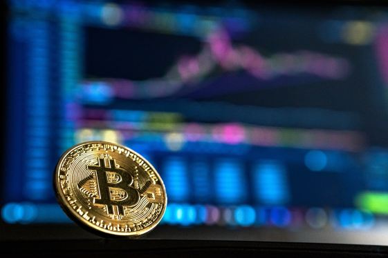 A bitcoin token in front of charts